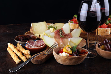 Italian antipasti wine snacks set. Cheese variety, Mediterranean olives, seafood salad, Prosciutto di Parma, tomatoes, anchovy and wine in glasses
