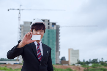 Business men holding white card at construction site.