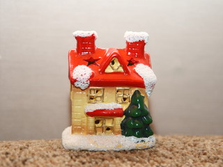 A small toy house in a snow outfit and a red roof.