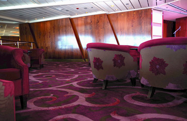 Flower pattern on back of arm chairs inside lounge bar onboard luxury cruise ship with wooden wall...