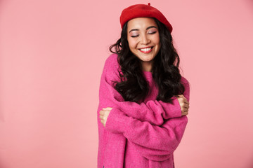 Image of beautiful asian girl wearing beret smiling and hugging herself