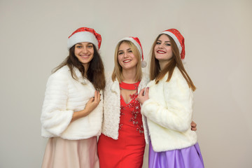 Happy friends at new year's party celebrating. Three women in elegant evening dresses and fur jackets