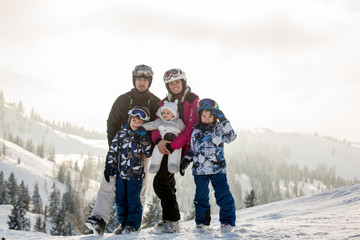 Beautiful family with kids, skiing in a scenery area in Austrian Alps on sunset, enjoying the view