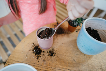 Little girl digs up the ground for rosetting with a spoon