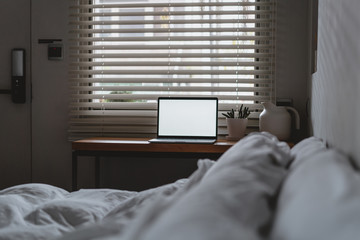 laptop with copy space empty screen and bed with white sheets