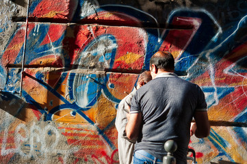 man from behind standing in front of a mural painted in an alley in naples,