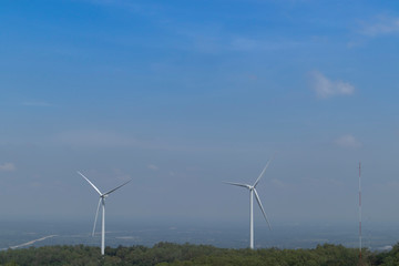 Fototapeta premium Mountain wind turbines for generating electricity Behind the mountains in the sky there are white clouds on a sunny and foggy day.