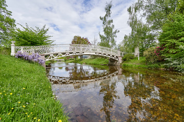 A beautiful white wrought iron bridge for pedestrians over a river in the European city of Baden Baden. Landscape with a bridge over a narrow river