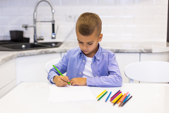 A boy looking while painting on a white paper