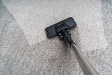 Vacuum cleaner is cleaning dirty carpet. Housework concept.
