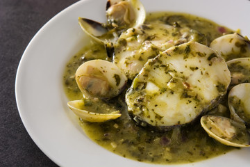 Hake fish and clams with green sauce on black background. Typical spanish recipe.	