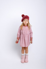 cute happy little girl in mittens, gloves and a winter hat on a white background in full growth