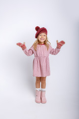 cute happy little girl in mittens, gloves and a winter hat on a white background in full growth