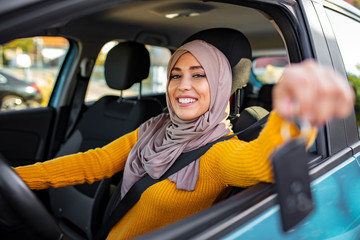 Happy arabian woman holding car key in new vehicle. Muslim woman in her new car. Happy arabian...