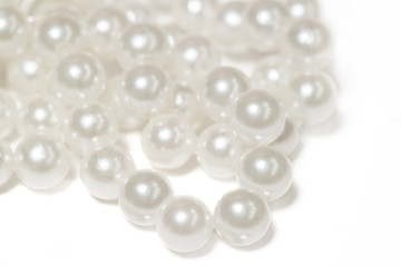 Necklace with  shining white pearl lie in a bunch form isolated background macro