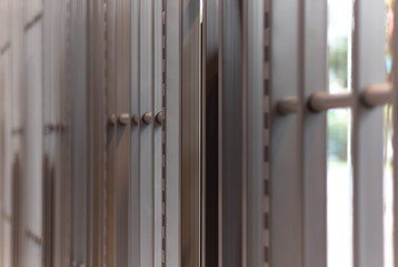 iron bars, metal grating or prison cell, bright blurred outdoor background