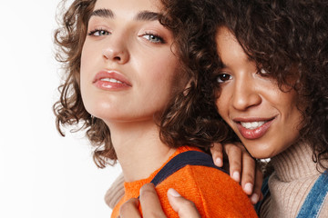 Portrait of pretty multinational women looking at camera and hugging