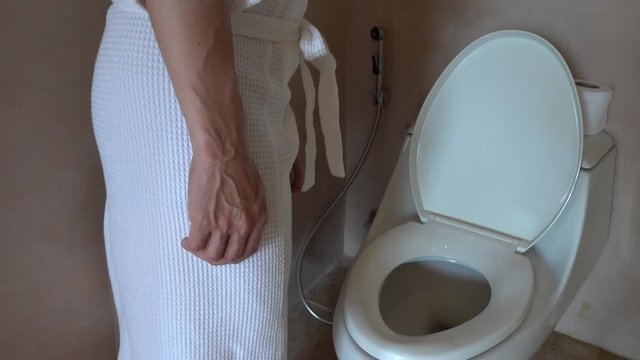 Man hand finger pushing button and flushing toilet