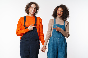 Portrait of joyful women pointing fingers at each other