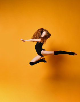 Young sport woman gymnastics doing jumping fitness exercise at sport gym jump on yellow