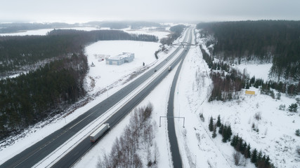 Obraz premium Freeway passing through the winter forest. The road with cars goes away to the horizon line. Aerial view.