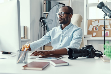 Handsome young African man using computer while working in the modern office
