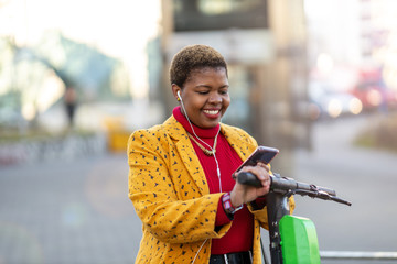 Young woman with electric scooter checking her smartphone