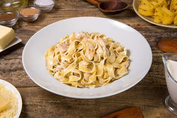 Chicken fettuccine alfredo on an old rustic wooden table. Selected focus.