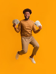 Super happy afro guy celebrating victory, holding lot of money