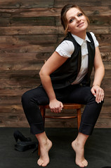 Naklejka premium Portrait of an adult pretty woman 40 years old with good makeup on a background of wood. Sits on a chair right in front of the camera with a smile. Business concept.