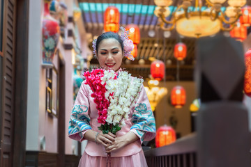 Asian woman in pink traditional chiness dress stand at balcony ,hand hold willow bouquet flower,and couple man and woman stand together behide,feel happy and hope.