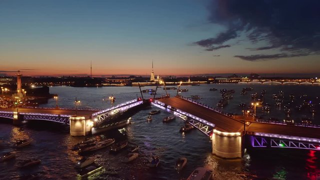 Aerial photography of night St. Petersburg. Drawbridge opens, tourists watch from the ships