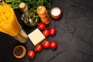 Cherry tomatoes, spaghetti, wooden cutting board, knife. Garlic, olive oil. Cooking background. Space for text. Ingredients for cooking. Cooking dinner. Selective focus. Food background