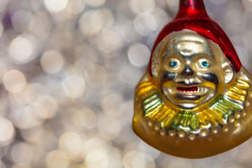 Vintage decorative christmas bauble in a shape of a crown jester against a colorful bokeh blury star background.