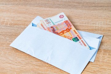 Envelope with ruble bills. Bribe. A stack of large ruble notes protrudes from a white envelope.