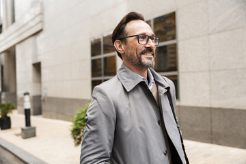 Image of handsome joyful businessman smiling while walking