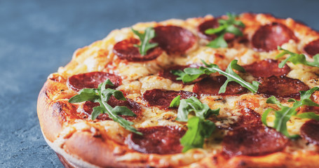 Pepperoni Pizza with Mozzarella cheese, salami, Tomato sauce, pepper, Spices and Fresh arugula. Italian pizza on Dark grey black slate background