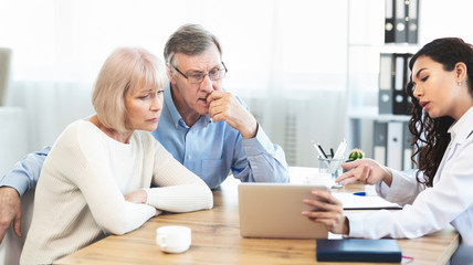 Mexican doctor explaining diagnosis to elderly couple