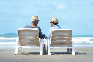 Asian Lifestyle senior couple sitting on chair beach.  People old happy in love romantic and relax...