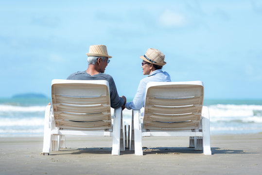 Asian Lifestyle senior couple sitting on chair beach.  People old happy in love romantic and relax time on the sand beach. Tourism elderly family travel leisure and activity after retirement summer.