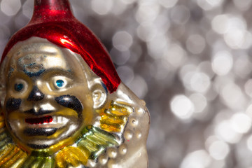 Vintage decorative christmas bauble in a shape of a crown jester against a silver bokeh blury star background.