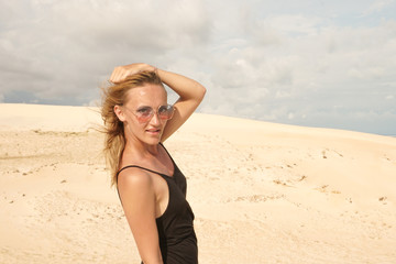 Fototapeta na wymiar The girl in black dress posing in the desert