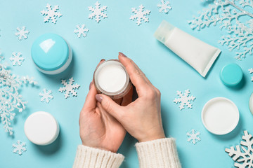 Woman using winter cream on blue.