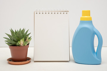 Laundry tips mock up. Detergent bottle and blank page notepad with copy space on white background.