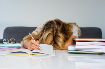 Woman student boring reading book at library with a lot of books in university. A sudent disheartened reading book for examination