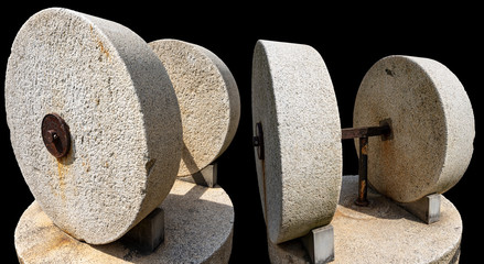 Two old millstones for the production of olive oil isolated on black background, Italy