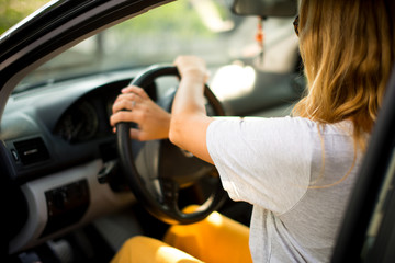 Fototapeta na wymiar Young beautiful blonde hair girl with driving a car. Confident and beautiful. Rear view of attractive young woman in casual wear looking forward her while driving a car.