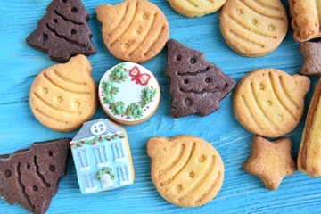 Set of cute homemade gingerbread cookies for christmas on wooden blue background. New year biscuits with beautiful iced decoration on textured turquoise backdrop. Traditional gingerbread cookies 