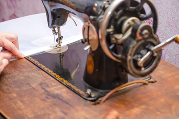 Hands of a woman who sews on an old sewing machine close up