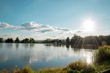 Beautiful fish pond in Badin, near Banska Bystrica, Slovakia. Fishing place. Blue sky and clouds over the lake. Mirror reflection in standing water. Beautiful slovak nature.